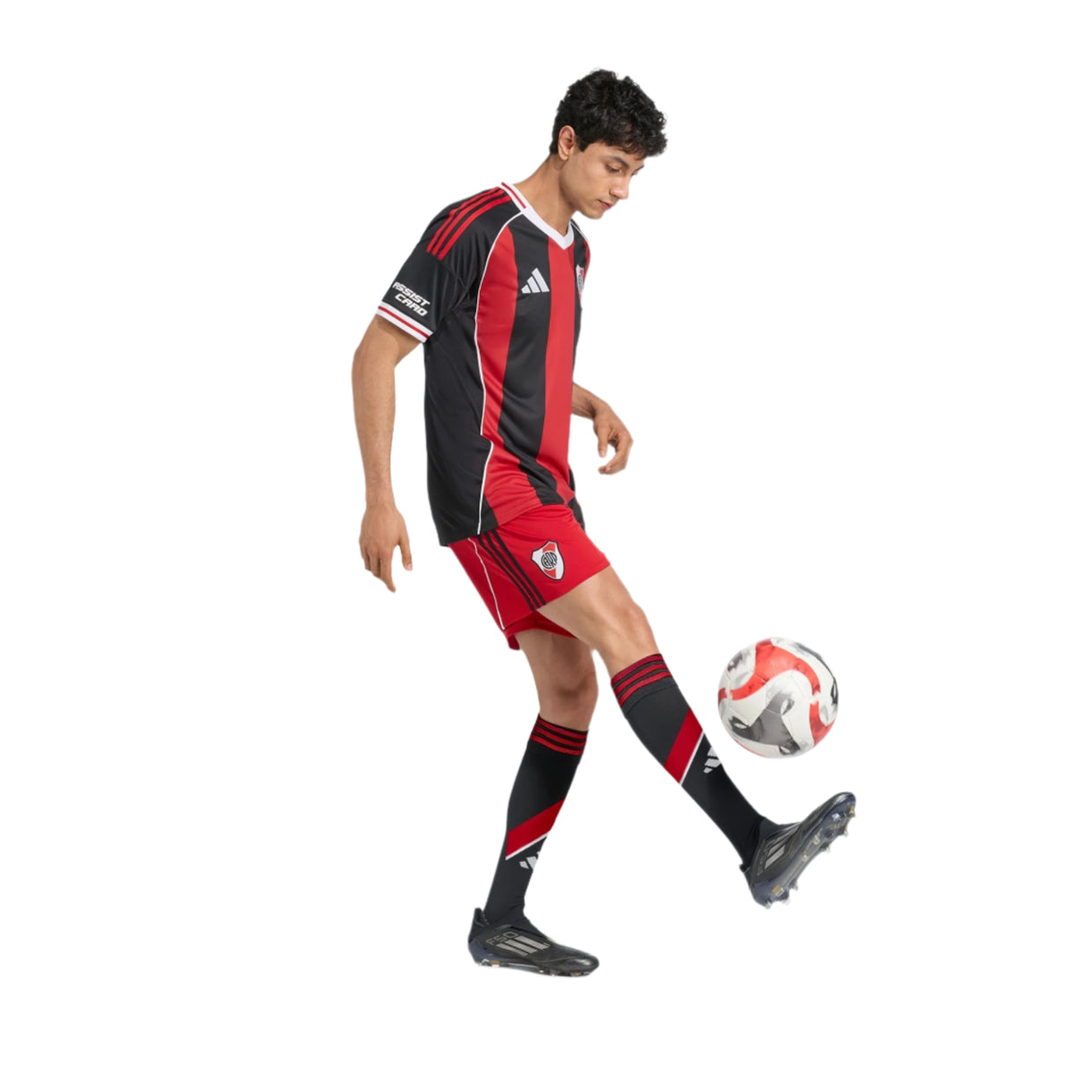 Person wearing a black and red soccer uniform with Adidas logo, kicking a soccer ball on a white background